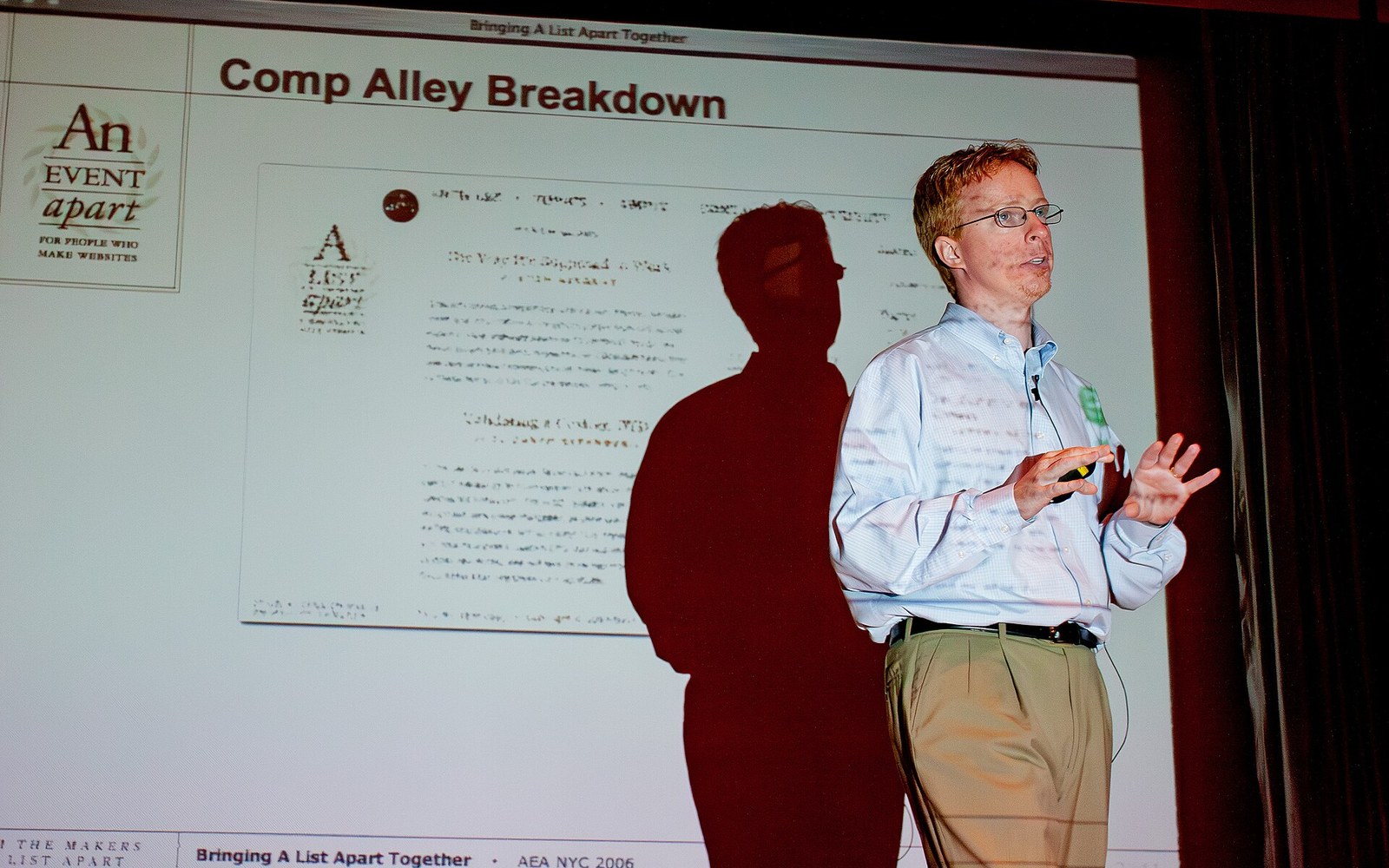 Speaker gestures while presenting a slide titled "Comp Alley Breakdown" at a conference
